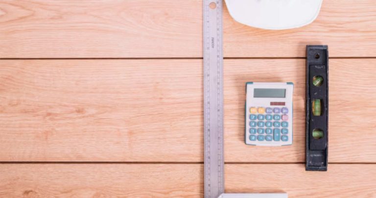 un ecran de laptop care afiseaza calculatorul de suprafata langa niste placi de parchet laminat