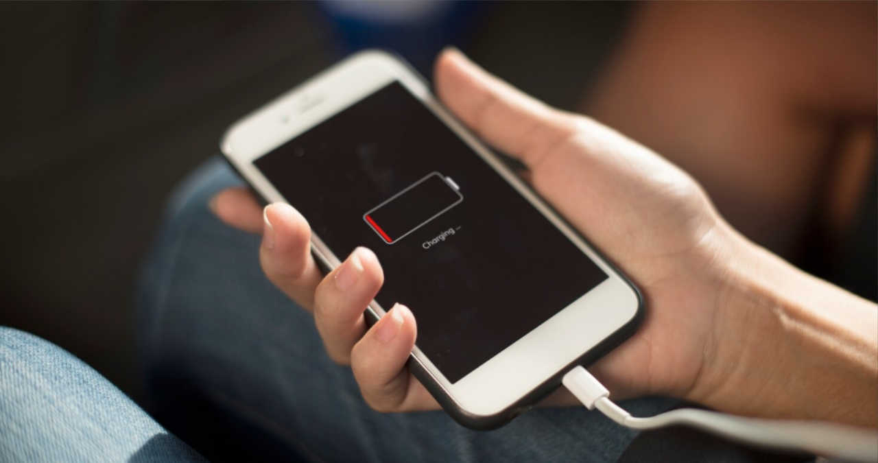 persoana curatand cu o scobitoare de lemn portul de incarcare al unui telefon mobil defect