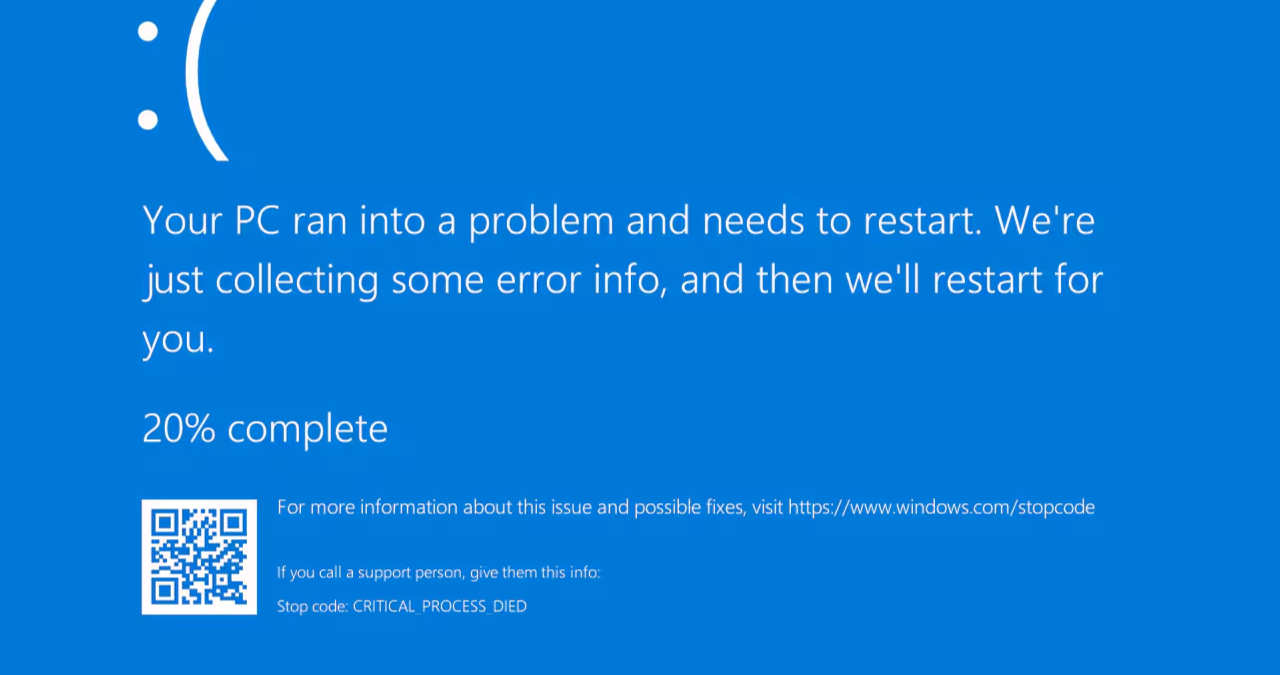 un monitor de calculator pe care este afisata eroarea de ecran albastru din windows alaturi de un laptop