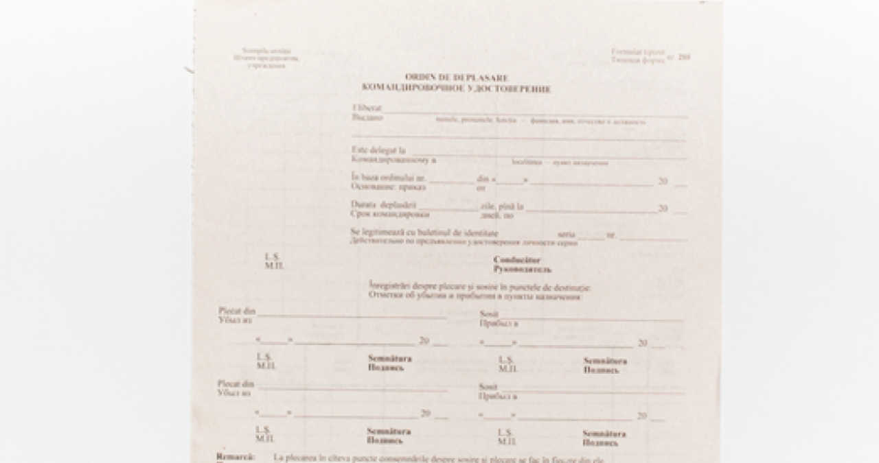 Un formular de ordin de deplasare completat, așezat pe un birou corporativ lângă o ștampilă