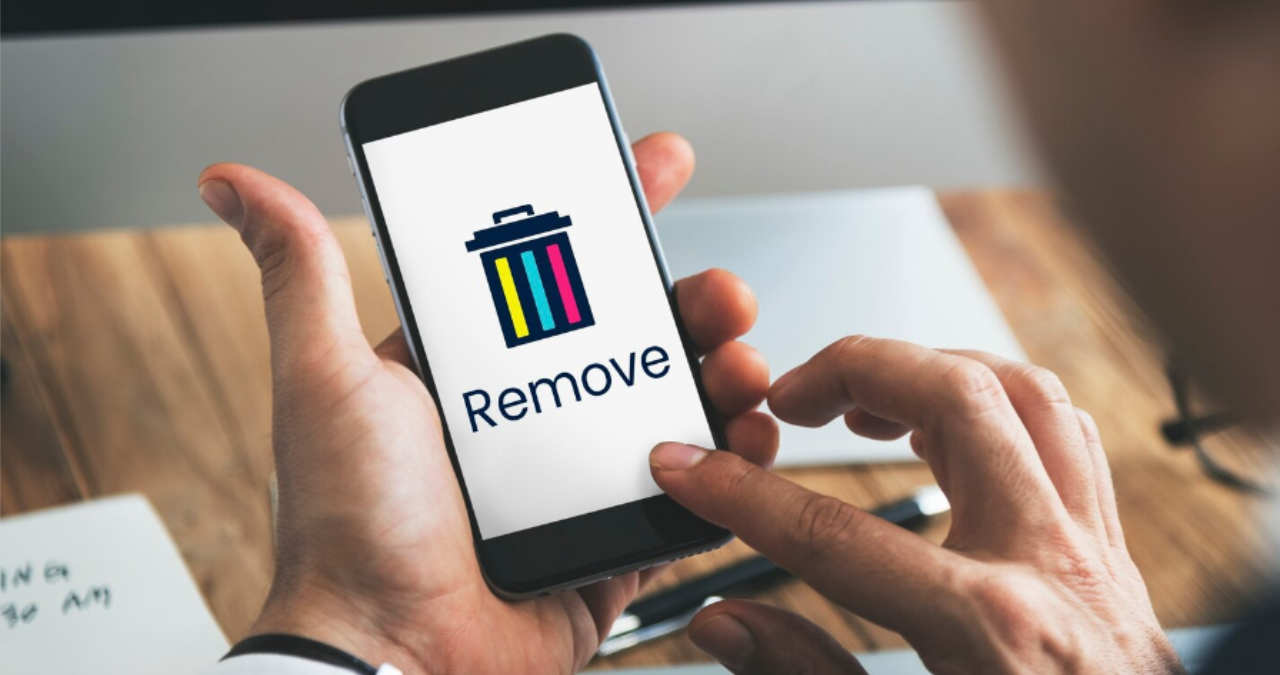 un deget care apasa pe ecranul unui iphone pe pictograma in forma de cos de gunoi din galeria foto