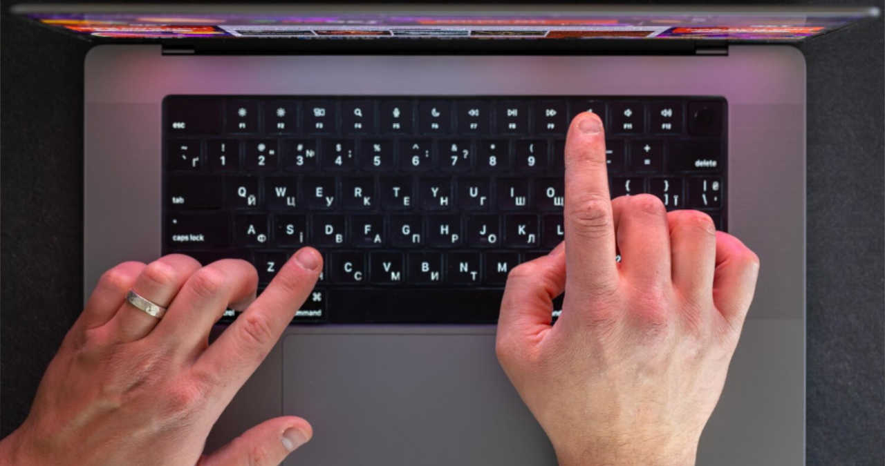 O mână folosind mouse-ul pentru a activa tastatura virtuală pe ecranul unui laptop Windows